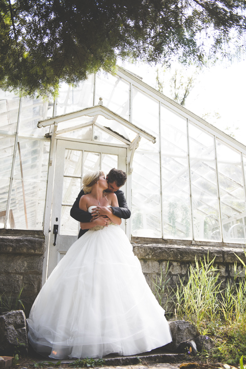 Bride and Groom romance eachother outside of a greenhouse at Blaylock's Mansion, by Nelson BC Kootenay wedding photographer Emilee Zaitsoff of Electrify Photograph