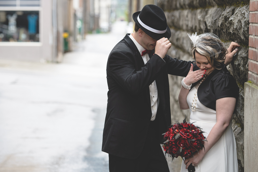 Bride and groom have a shy moment in an alley, 1920s theme, by Nelson BC Kootenay wedding photographer Emilee Zaitsoff of Electrify Photograph