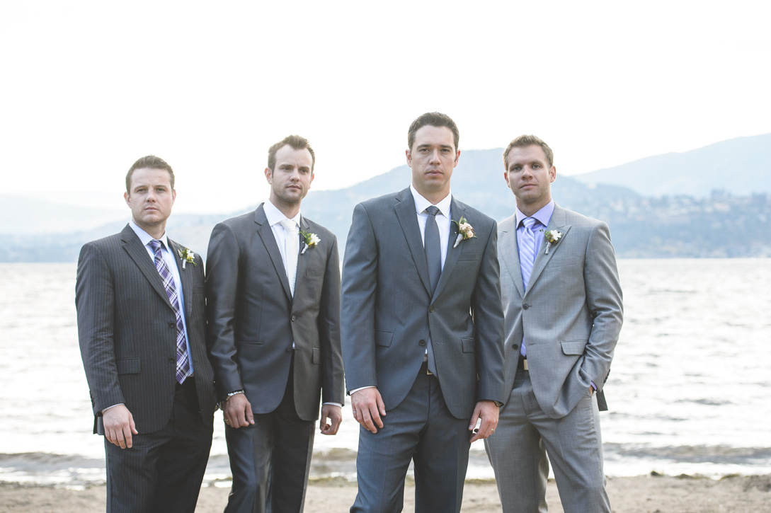 Groomsen put on their serious faces in sand by lake near Kelowna, BC, Okanagan by Nelson BC Kootenay wedding photographer Emilee Zaitsoff of Electrify Photography