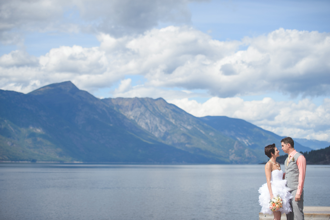 Bride and groom stand before epic vista of kootenay lake and mountains, sanca, by Nelson BC Kootenay wedding photographer Emilee Zaitsoff of Electrify Photograph